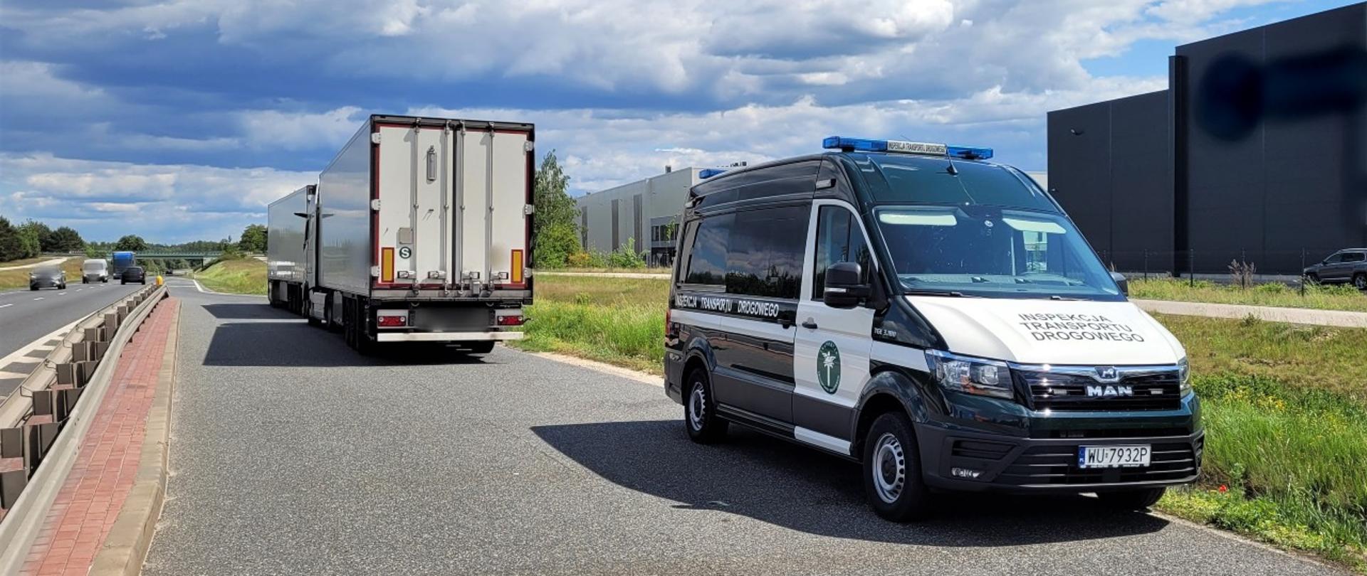 Na pierwszym planie (od prawej): oznakowany furgon mazowieckiej Inspekcji Transportu Drogowego stoi w zatoce przy krajowej „pięćdziesiątce” pod Mszczonowem. W tle: za furgonem ITD stoją dwa zatrzymane do kontroli ciągniki siodłowe z naczepami. Obok, po jezdni drogi krajowej, przejeżdżają samochody osobowe i samochody ciężarowe.