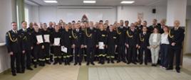 Pamiątkowe zdjęcie grupowe uczestników szkolenia podstawowego w zawodzie strażak z oficerami PSP oraz cywilnymi pracownikami ośrodka szkolenia uczestniczącymi w uroczystości zakończenia szkolenia