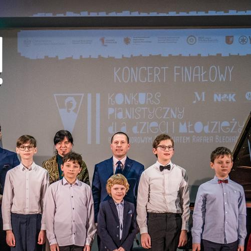 Fragment grupy laureatów wraz z jurorami VII Konkursu Pianistycznego dla dzieci i młodzieży pod honorowym patronatem Rafała Blechacza. W tle na ścianie napis: "koncert finałowy VII Konkursu Pianistycznego dla dzieci i młodzieży pod honorowym patronatem Rafała Blechacza.