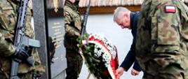 Na fotografii znajduje się Wojewoda Opolski Sławomir Kłosowski poprawiający wieniec premiera w otoczeniu żołnierzy