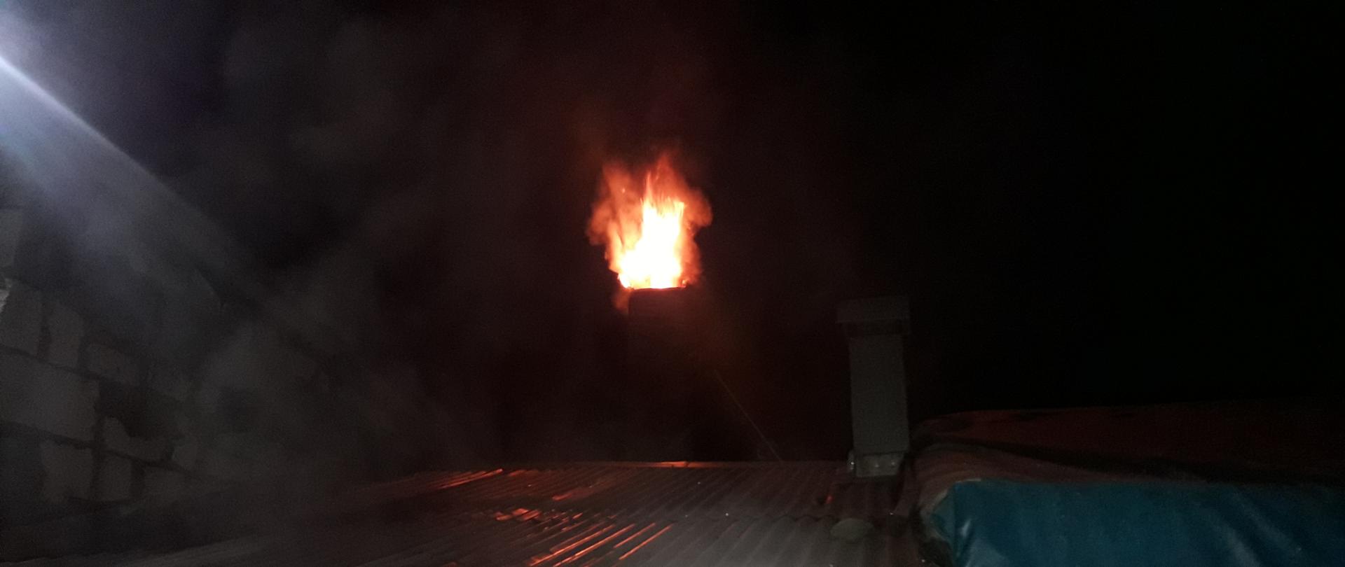 Palący się komin. Widoczne płomienie z niego wychodzące.