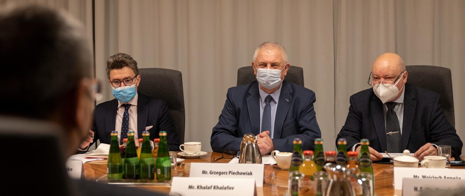 Wiceminister Grzegorz Piechowiak na spotkaniu z ambasadorem Azerbejdżanu siedzący za stołem z maseczką na twarzy