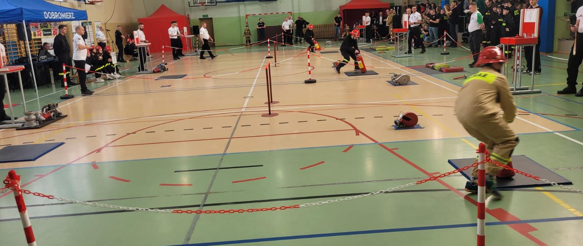 Członek Młodzieżowej Drużyny Pożarniczej pokonuje halowy tor przeszkód podczas zawodów sportowo‑pożarniczych.