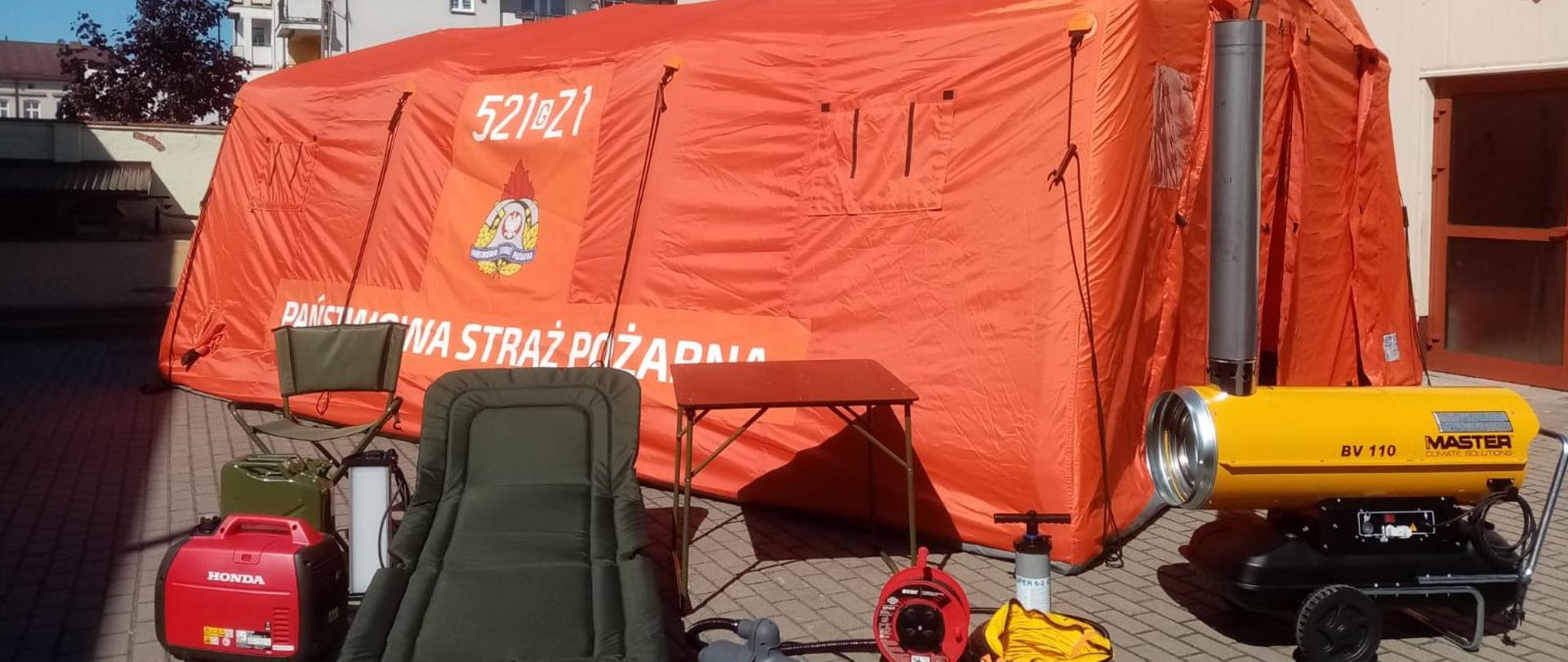 Foto przedstawia agregat prądotwórczy, butla stalowa 6 l, reduktor butlowy 200/300 bar, nagrzewnica olejowa 20 kW, pompka, lampy, przedłużacz, kanister 20 l, łóżka polowe 10 szt., krzesła składane 10 szt. oraz stół polowy