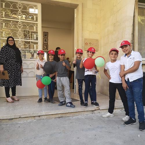 Grupa dzieci stoi przed wejściem do szkoły