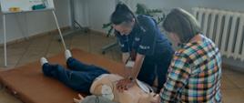 Funkcjonariusze policji podczas ćwiczeń praktycznych z pierwszej pomocy przy użyciu defibrylatora automatycznego i manekina umożliwiającego wykonanie resuscytacji krążeniowo - oddechowej
