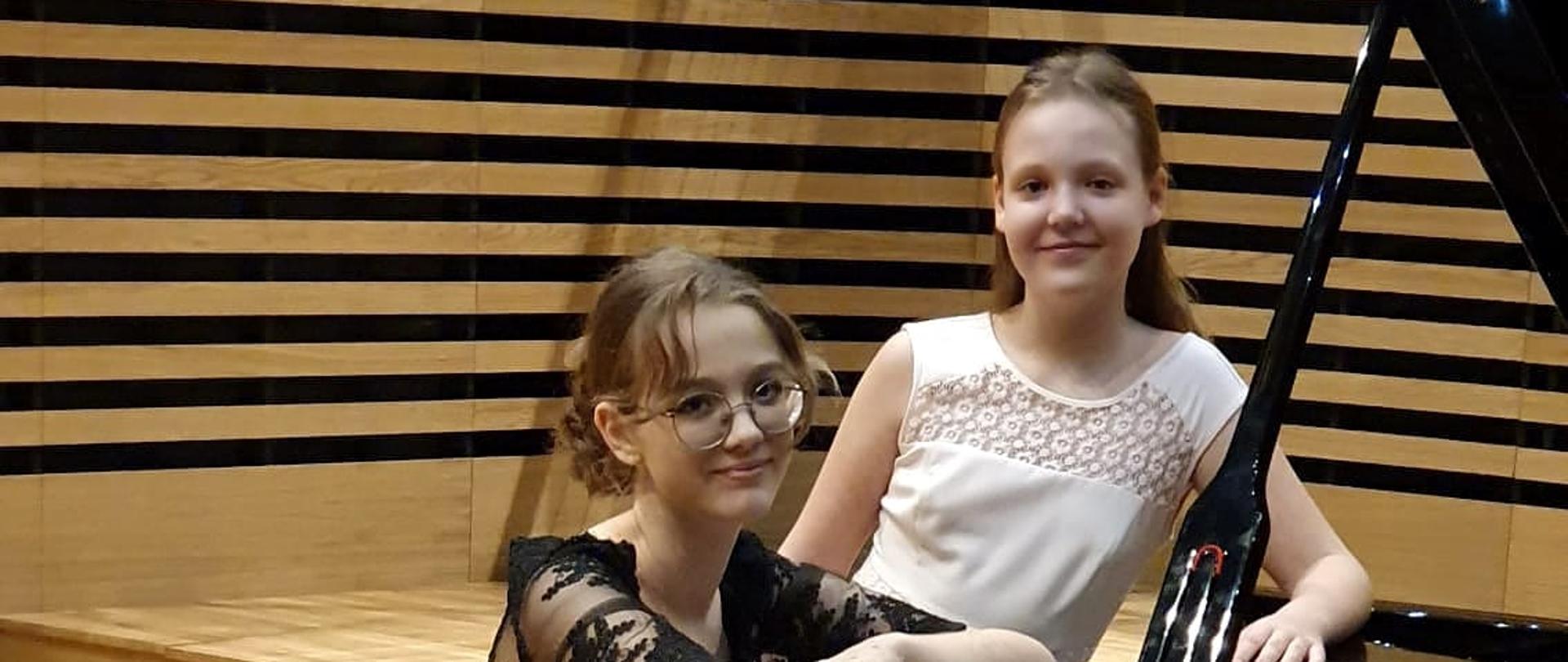 Dwie uczennice przy fortepianie na scenie sali koncertowej PSM