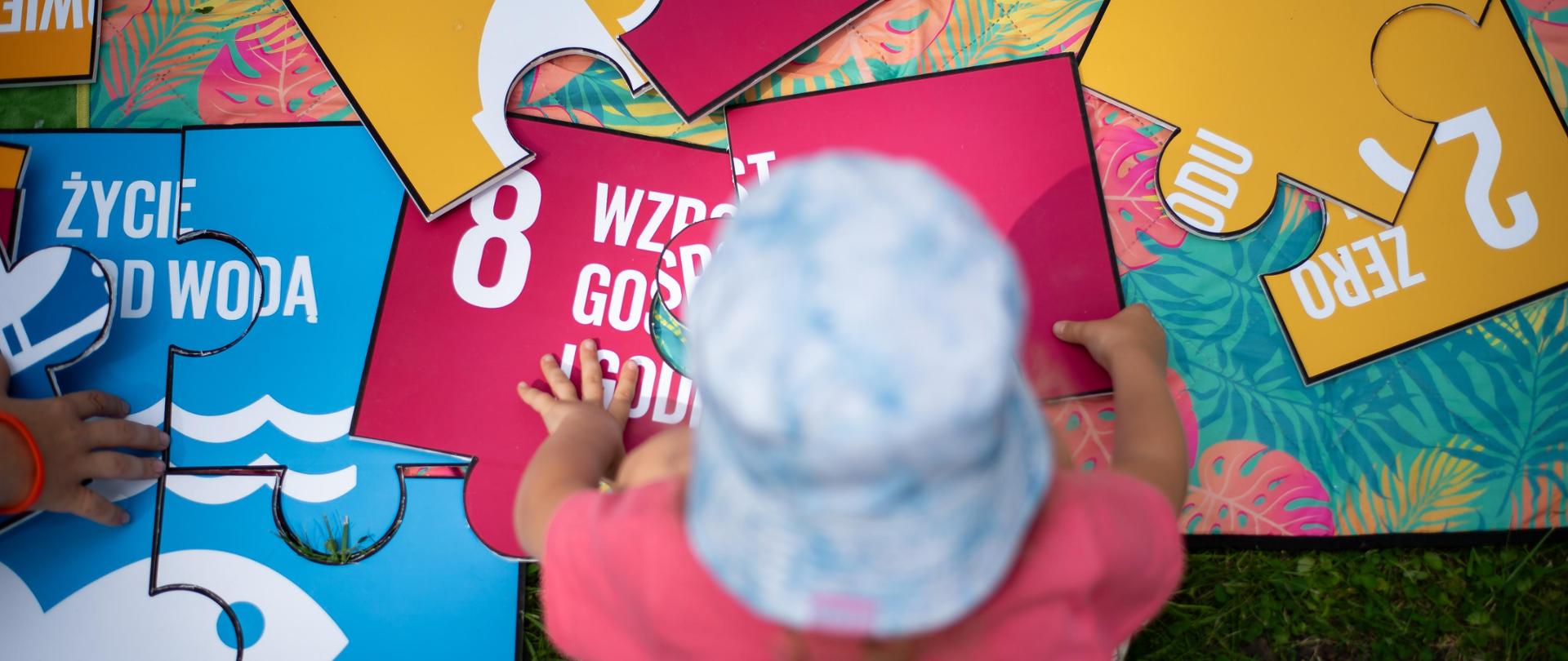 Małe dziecko siedzące na macie z puzzlami.