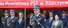 przy mównicy przemawia st. bryg. Daniel Dryniak Z-ca Podkarpackiego Komendanta Wojewódzkiego PSP w tle zaproszeni goście