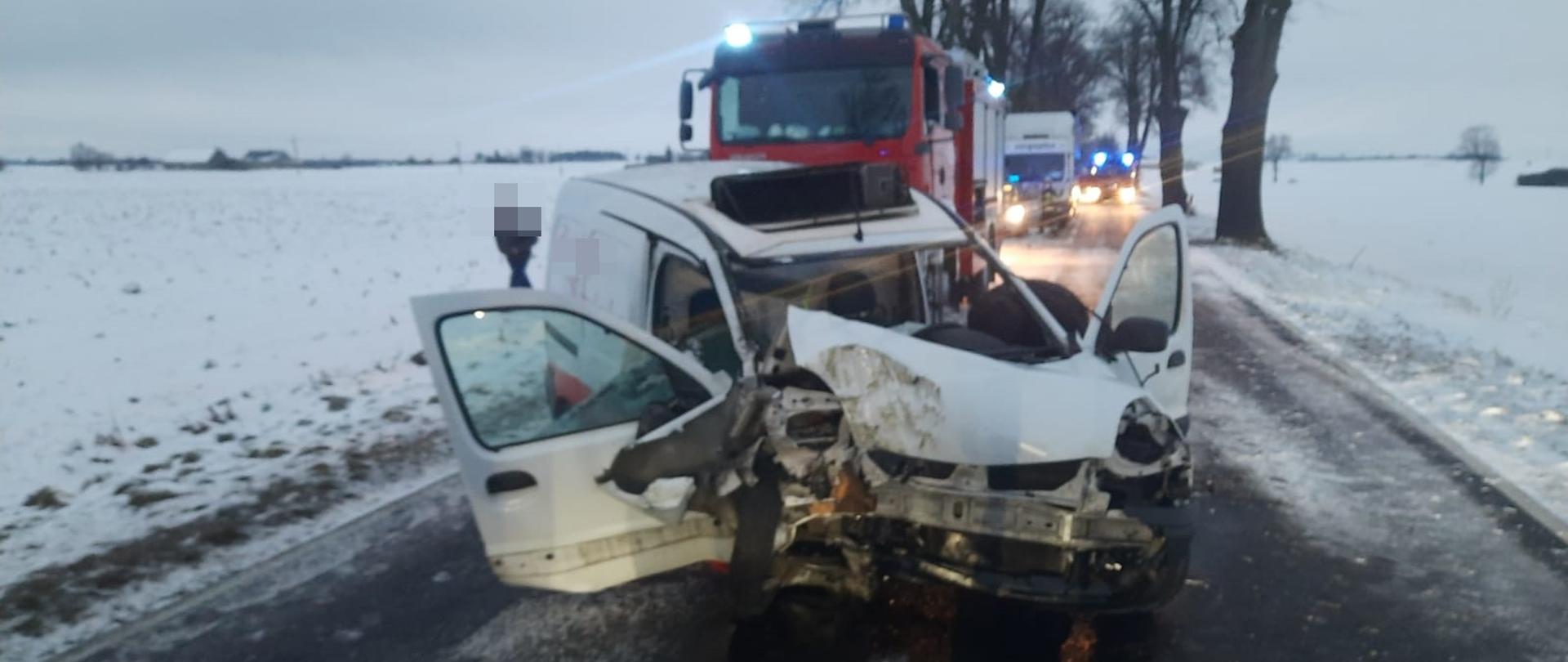 Na zdjęciu widać rozbite auto oraz w tle wóz straży pożarnej 