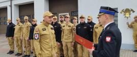 Zdjęcie przestawia asp. Marcina Kucach odbierającego list gratulacyjny z okazji jubileuszu 25 lat służby i pracy z rąk st. kpt. mgr Krzysztofa Natuckiego Komendanta Powiatowego PSP w Brodnicy
