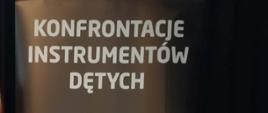 Napis na ciemnym tle "Konfrontacje Instrumentów Dętych"