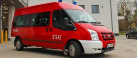 Ford Transit KP PSP Legionowo. Zdjęcie przed budynkiem komendy pojazd czerwony z napisem straż na przednich drzwiach oraz numerze operacyjnym 470M56