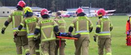 Ćwiczenia na lotnisku AZL w Zielonej Górze - strażacy przenoszą osobę ranną do karetki