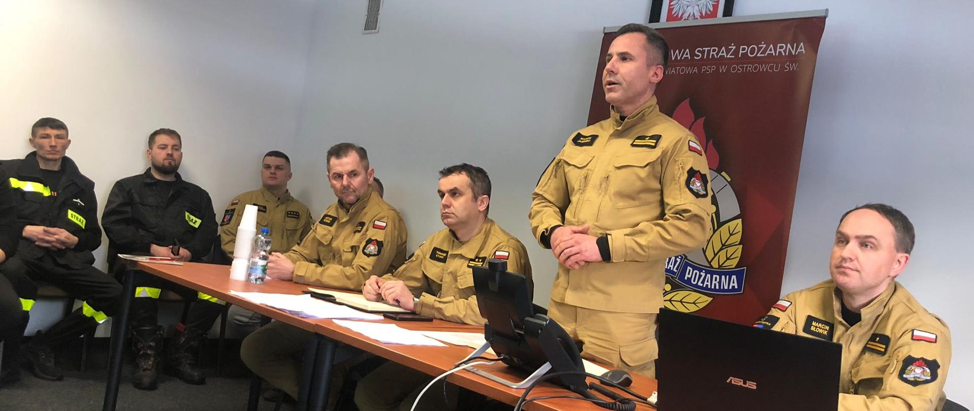 Na zdjęciu widoczny jest Komendant Powiatowy Państwowej Straży Pożarnej w Ostrowcu Św., Zastępca Komendanta Powiatowego Państwowej Straży Pożarnej w Ostrowcu Św., funkcjonariusze PSP, przedstawiciele gmin oraz druhowie OSP w trakcie spotkania nt. strategii rozwoju ochrony przeciwpożarowej.