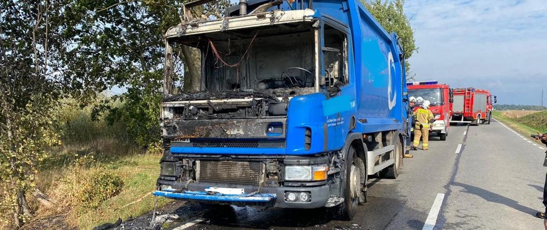 Widok spalonej kabiny śmieciarki oraz strażaków zabezpieczających miejsce zdarzenia