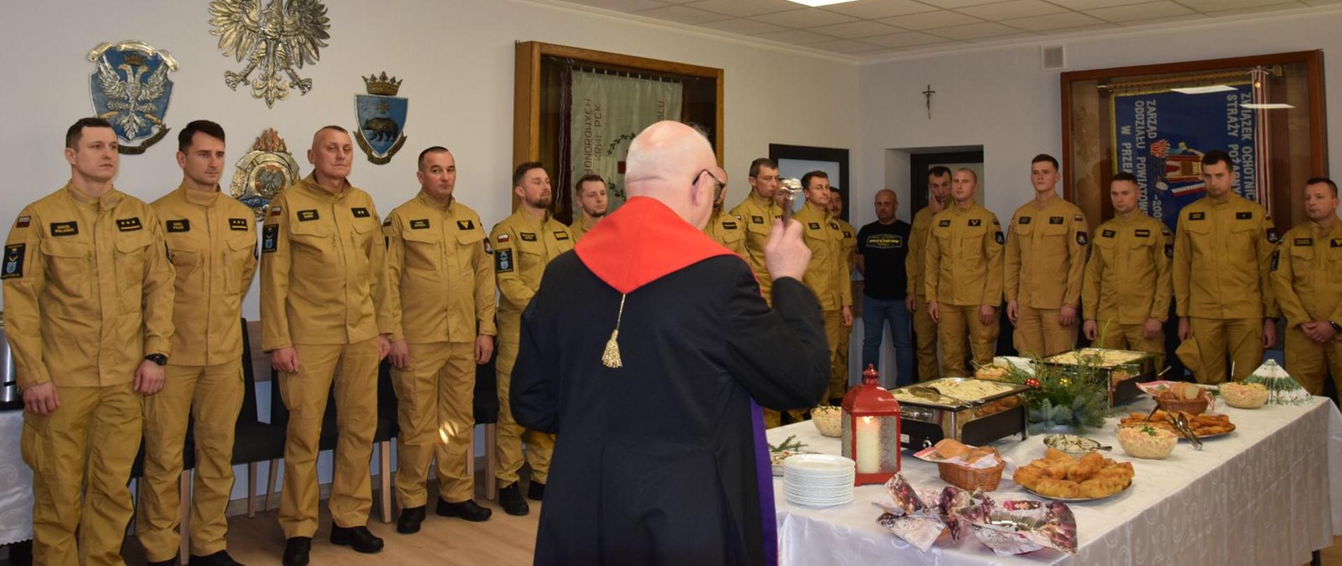 Na zdjęciu ks. prałat Mieczysław Rusin kapelan strażaków Archidiecezji Przemyskiej podczas święcenia pokarmów na stole wigilijnym, wokół stołu przemyscy strażacy 