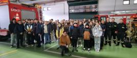 Wizyta w ramach akcji „Odwiedź strażnicę i salę edukacyjną typu Ognik” w KP PSP w Sokołowie Podlaskim 17.11.2023 r. - wspólne zdjęcie na garażu komendy