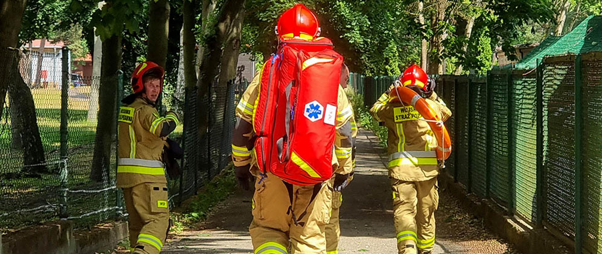 Zdjęcie przedstawia strażaków na chodniku w czasie akcji ratowniczej.