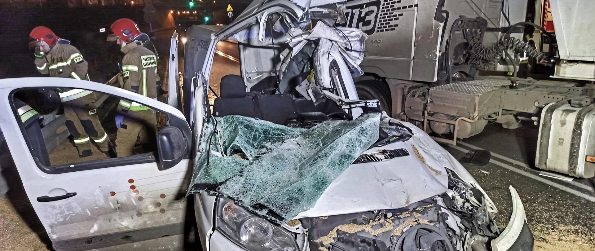 Uszkodzone auto dostawcze po przygnieceniu przez naczepę ciągnika siodłowego.