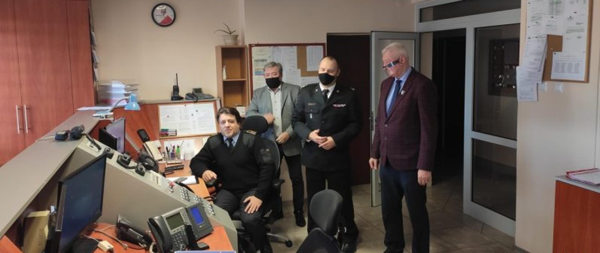 Od prawej starosta jasielski Adam Pawluś obok stoi Komendant Powiatowy PSP w Jaśle mł. bryg. Piotr Śmietana, następnie Naczelnik Wydziału Obrony Cywilnej Starostwa Powiatowego w Jaśle Tadeusz Walczyk. Przed komputerem siedzi Dyżurny Operacyjny asp. sztab. Hubert Folczyk.