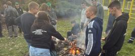 uczniowie piekący kiełbaski przy ognisku w szkolnym ogrodzie