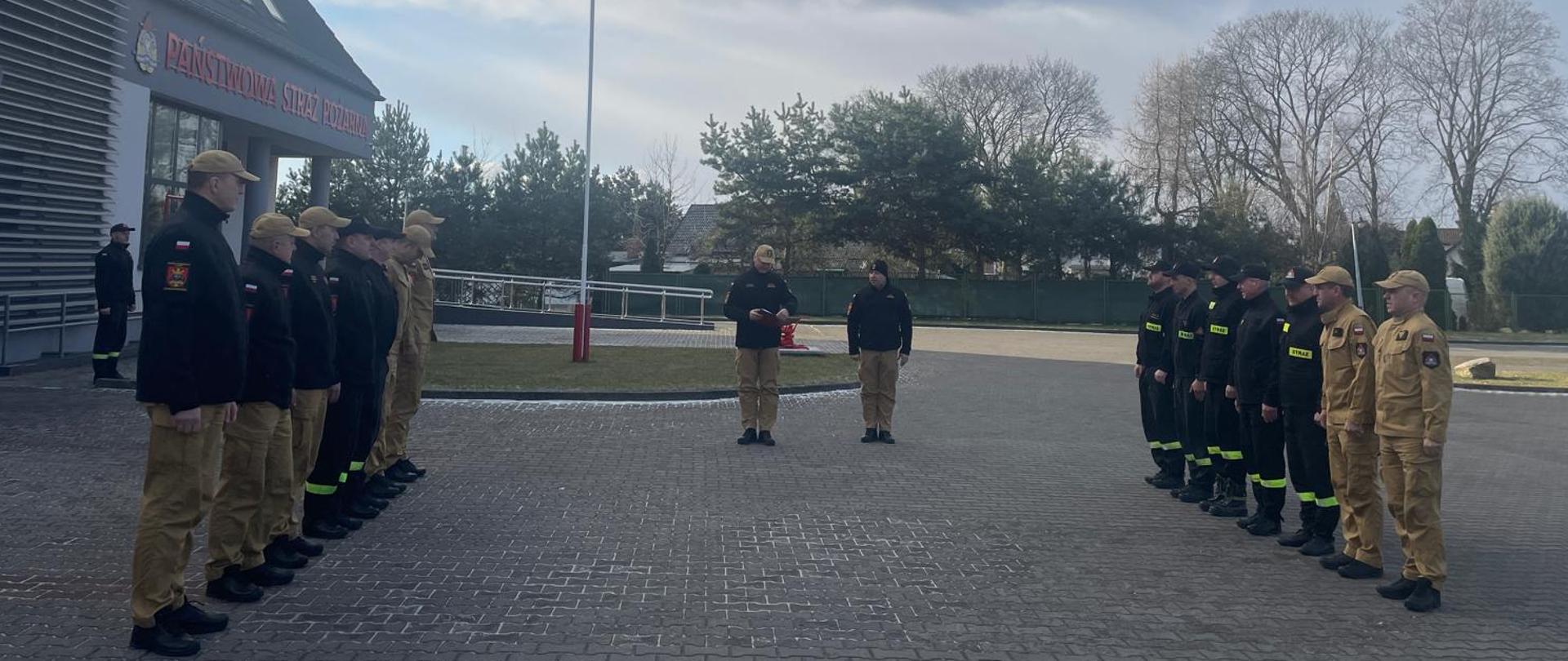 Na zdjęciu komendant powiatowy PSP odczytuje decyzje personalną przez zebranymi strażakami