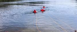 Na zdjęciu widoczni ratownicy podczas działań związanych z ewakuacją poszkodowanego z wody. Ratownicy oraz poszkodowany zabezpieczeni są w kamizelkę ratunkową, kask oraz asekurowani przy pomocy liny. 
