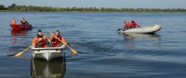 Ćwiczenia z udziałem SGRWN. Zdjęcie przedstawia zbiornik retencyjny w Jutrosinie. Na akwenie, w dwóch łódkach i jednym pontonie znajduje się po dwóch strażaków. W tle drzewa.