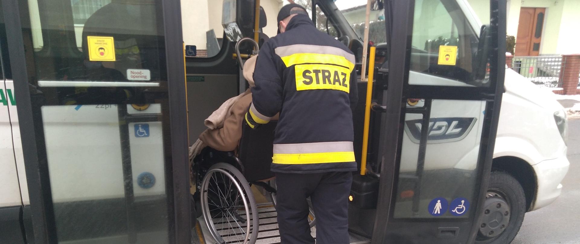Strażak wprowadza do auta osobę na wózku 