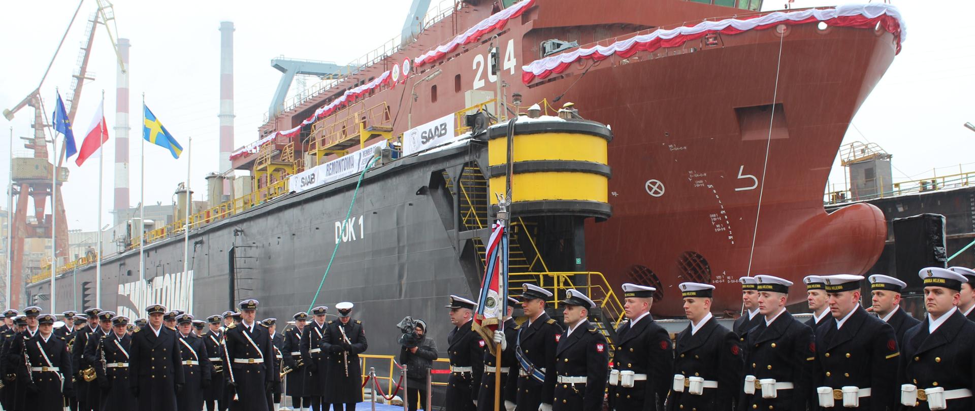 statek wodowany, przed nim marynarze w strojach galowych