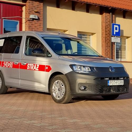 Samochód lekki VW Caddy w kolorze srebrnym przed strażnicą.