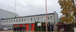 Poczet flagowy podwiesza flagę na masz strażacy ustawienie w dwóch rzędach naprzeciwko siebie stoją na baczność oddając honory.