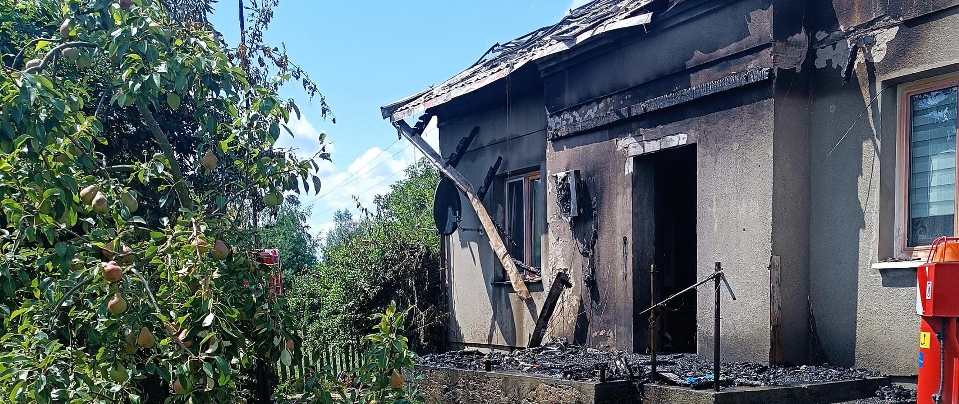 Zdjęcie przedstawia wejscie do obiektu oraz spaloną altane.