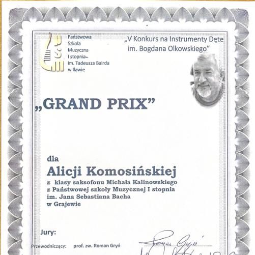 Dyplom przyznany Alicji Komosińskiej za zdobycie Grand Prix w V Konkursie na Instrumenty Dęte im. Bogdana Olkowskiego. Uczennica klasy saksofonu Michała Kalinowskiego z Państwowej Szkoły Muzycznej I stopnia im. Jana Sebastiana Bacha w Grajewie. Dokument zawiera logotyp szkoły muzycznej i zdjęcie patrona konkursu.

