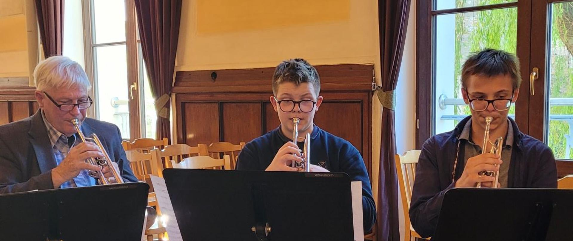 Na zdjęciu widać po prawej stronie dwoje uczniów naszej szkoły grających na trąbce. Po lewej stronie przedstawiciel z Teksasu, który też gra na trąbce.