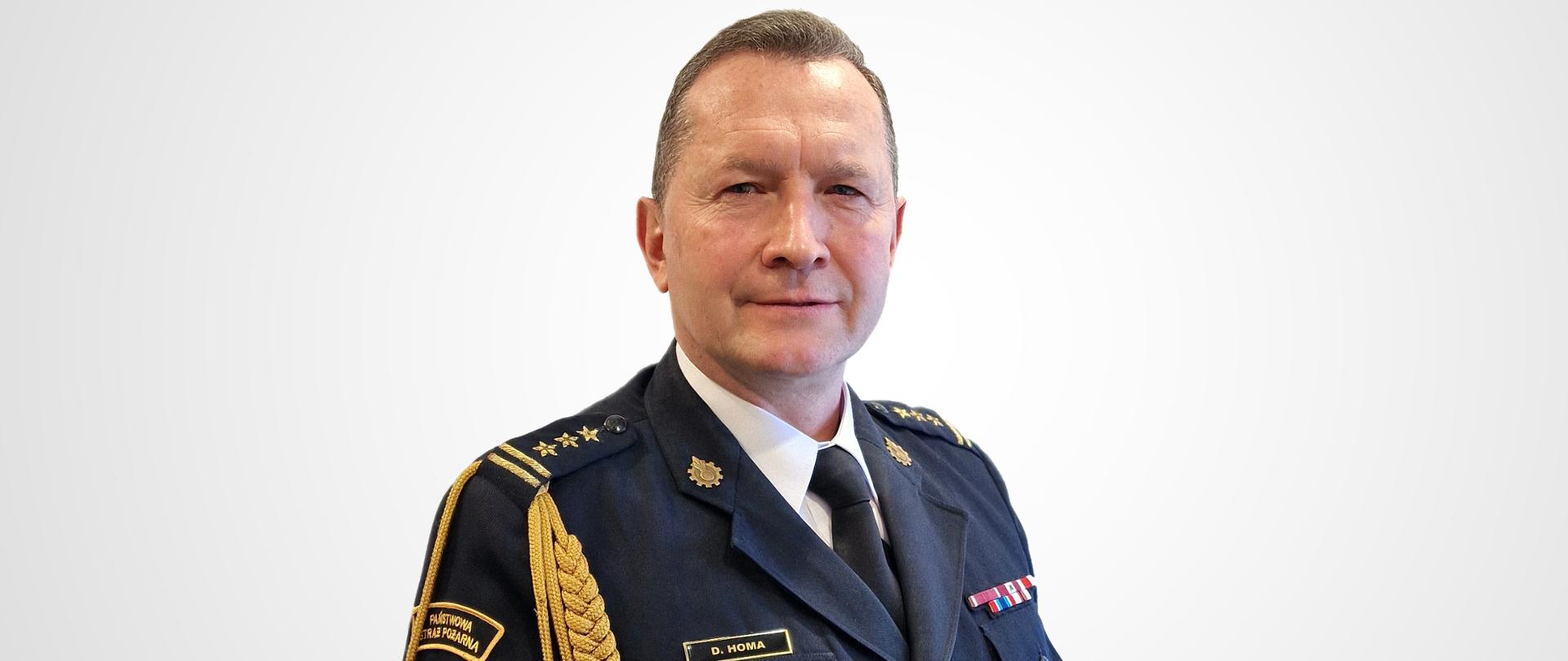 Na jasnym tle zdjęcie portretowe Zastępcy Podkarpackiego Komendanta Wojewódzkiego PSP st. bryg. Dariusza Homy w mundurze galowym