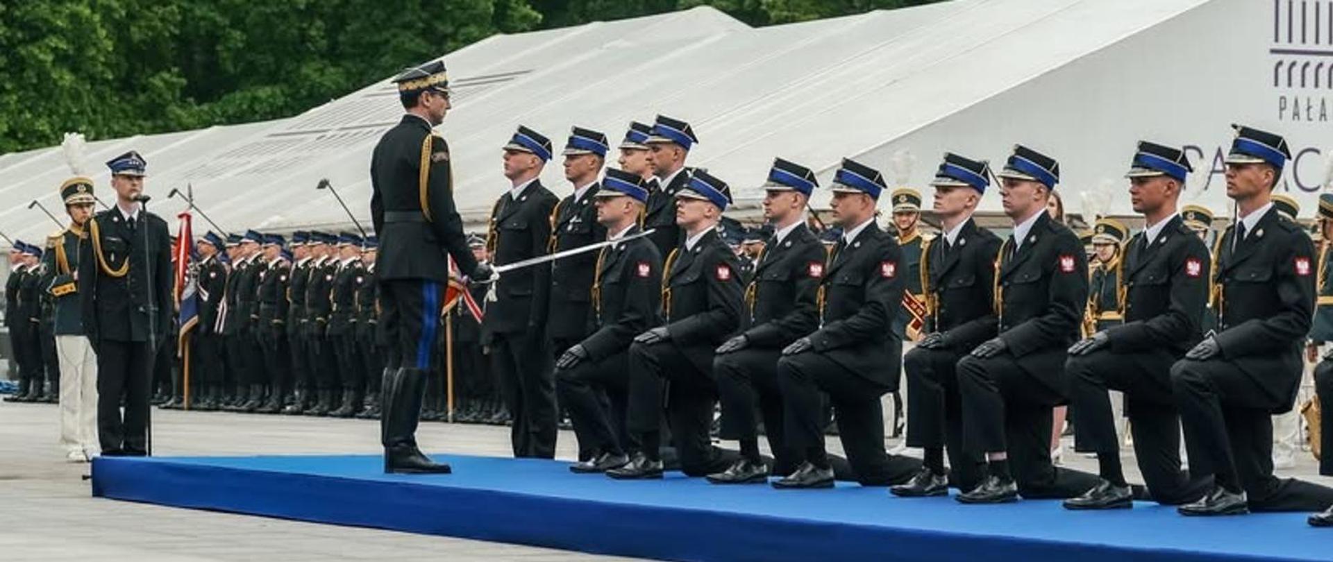 Na zdjęciu widać klęczących strażaków w mundurach służbowych.