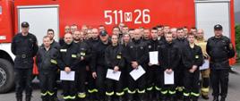 grupowe zdjęcie uczestników szkolenia i egzaminatorów na tle pojazdu gaśniczego