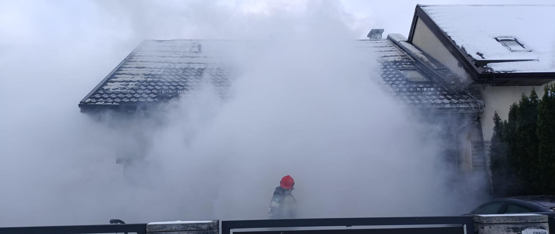 Strażak podczas działań związanych z pożarem budynku jednorodzinnego