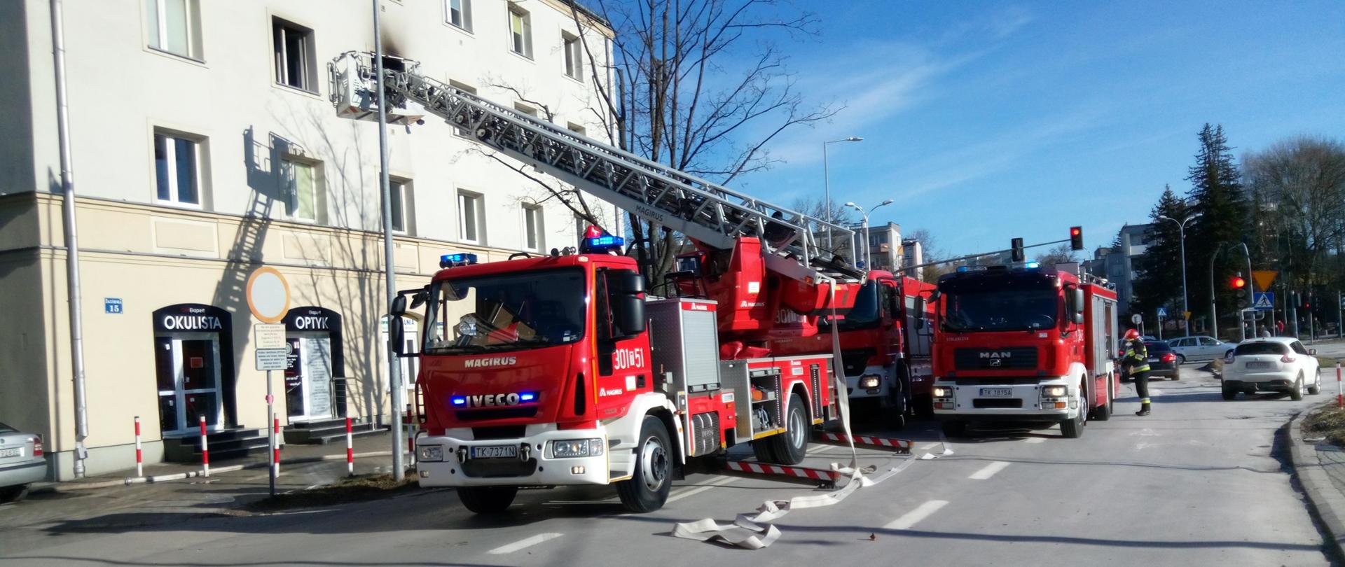 Na zdjęciu widzimy perspektywę ulicy Zagórskiej w Kielcach. Wzdłuż ulicy zaparkowane trzy samochody pożarnicze biorące udział w zdarzeniu. Po lewej budynek wielorodzinny gdzie wybuchł pożar.