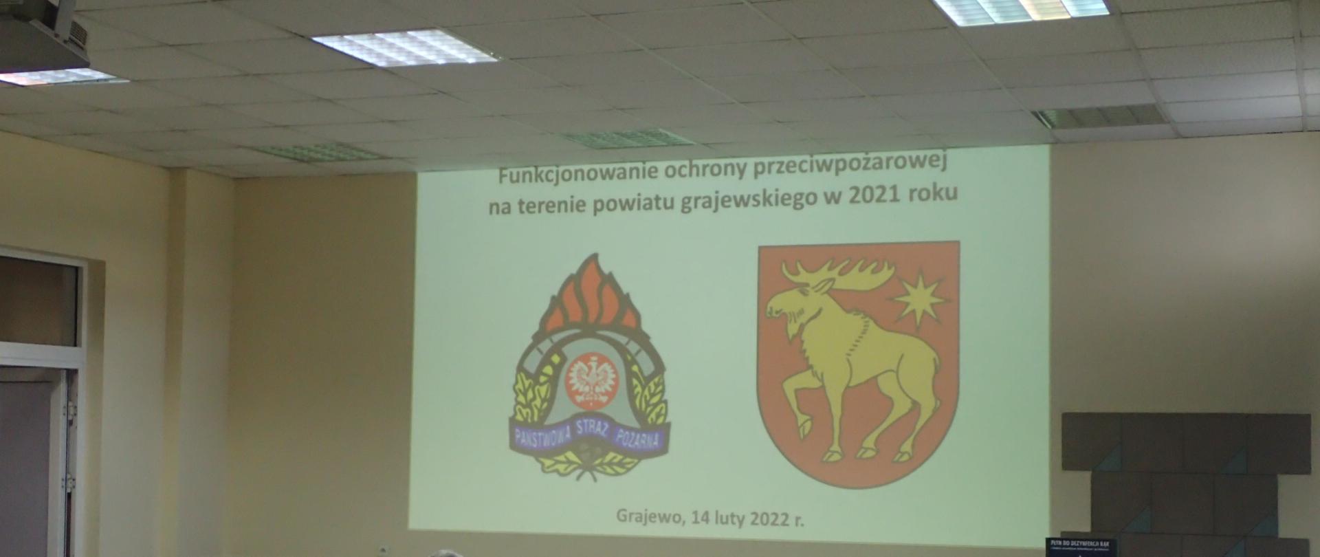 Logo PSP i herb powiatu grajewskiego wyświetlone na prezentacji multimedialnej