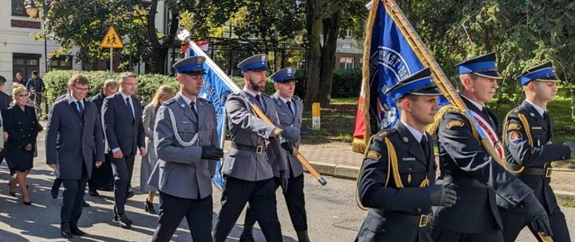 Poczty sztandarowe służb mundurowych maszerują. 