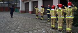 Strażacy salutują przy maszcie z flaga państwową