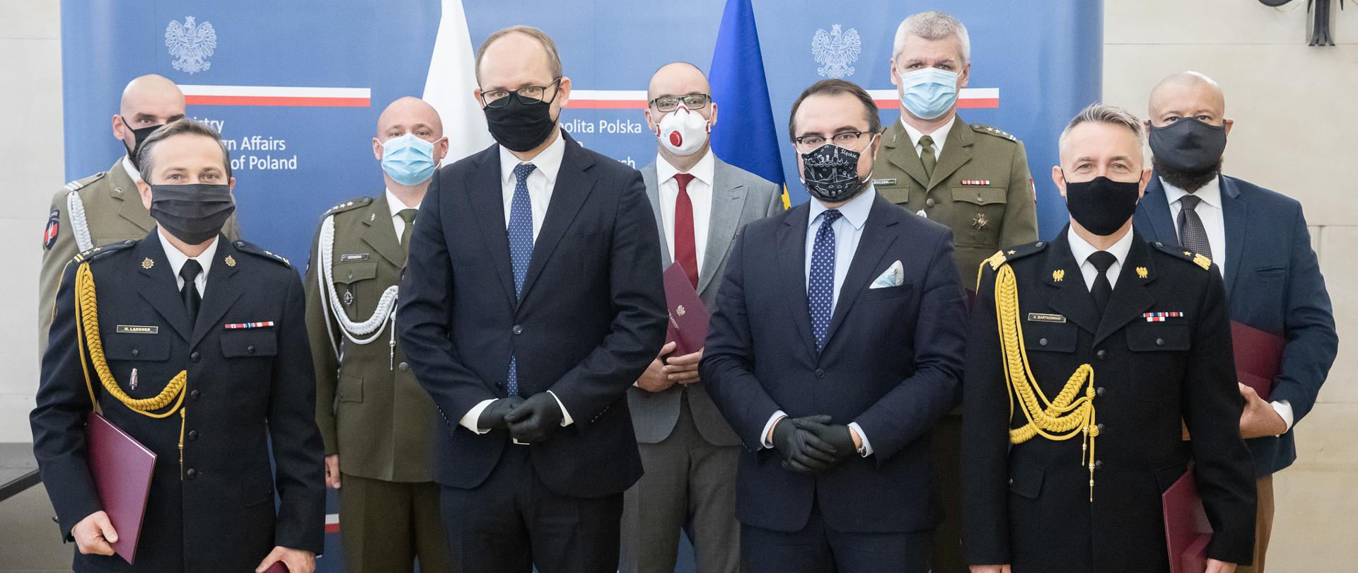 2020.10.02 Warszawa . Minister Pawel Jablonski . Minister Marcin Przydacz . Wreczenie odznak Bene Merito. Na zdjęciu także nadbryg. Andrzej Bartkowiak komendant główny PSP oraz bryg. Michał Langner z KG PSP – uczestnicy stoją w dwóch rzędach. Są w maseczkach.
Fot. Tymon Markowski / MSZ