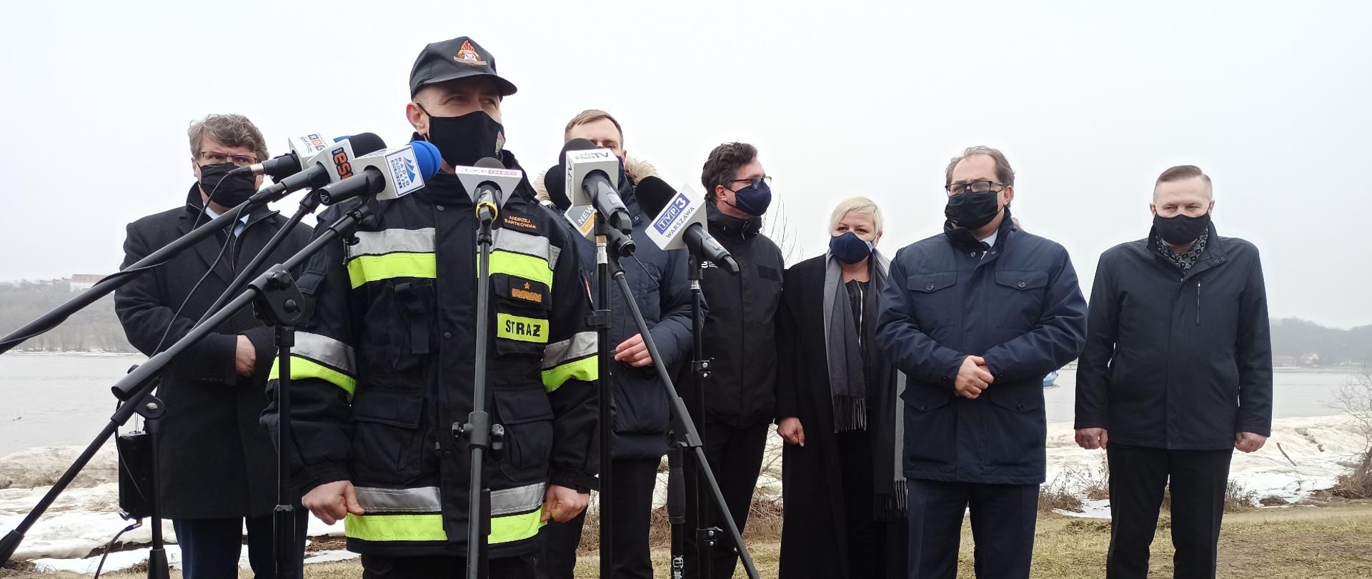 Przemawia do mikrofonów komendant główny PSP Andrzej Bartkowiak, w tle mężczyźni m.in. wiceminister SWiA Maciej Wąsik (po lewo)