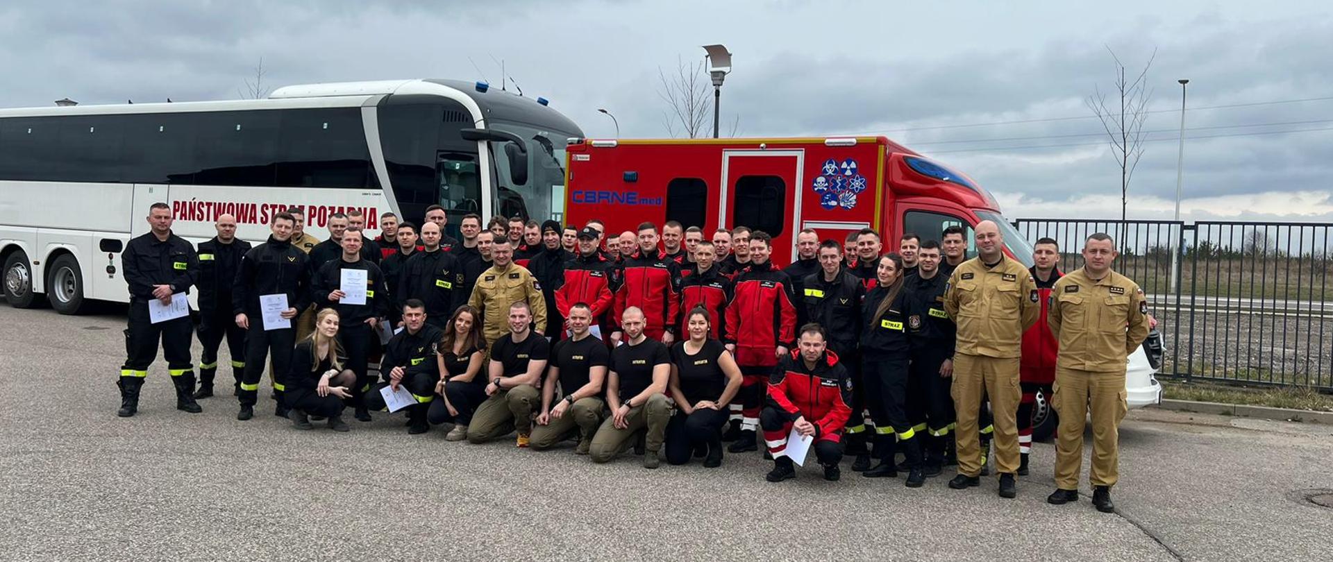 Zdjęcie grupowe na tle karetki i autobusu