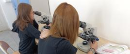 Uczennice obserwują preparaty pod mikroskopem