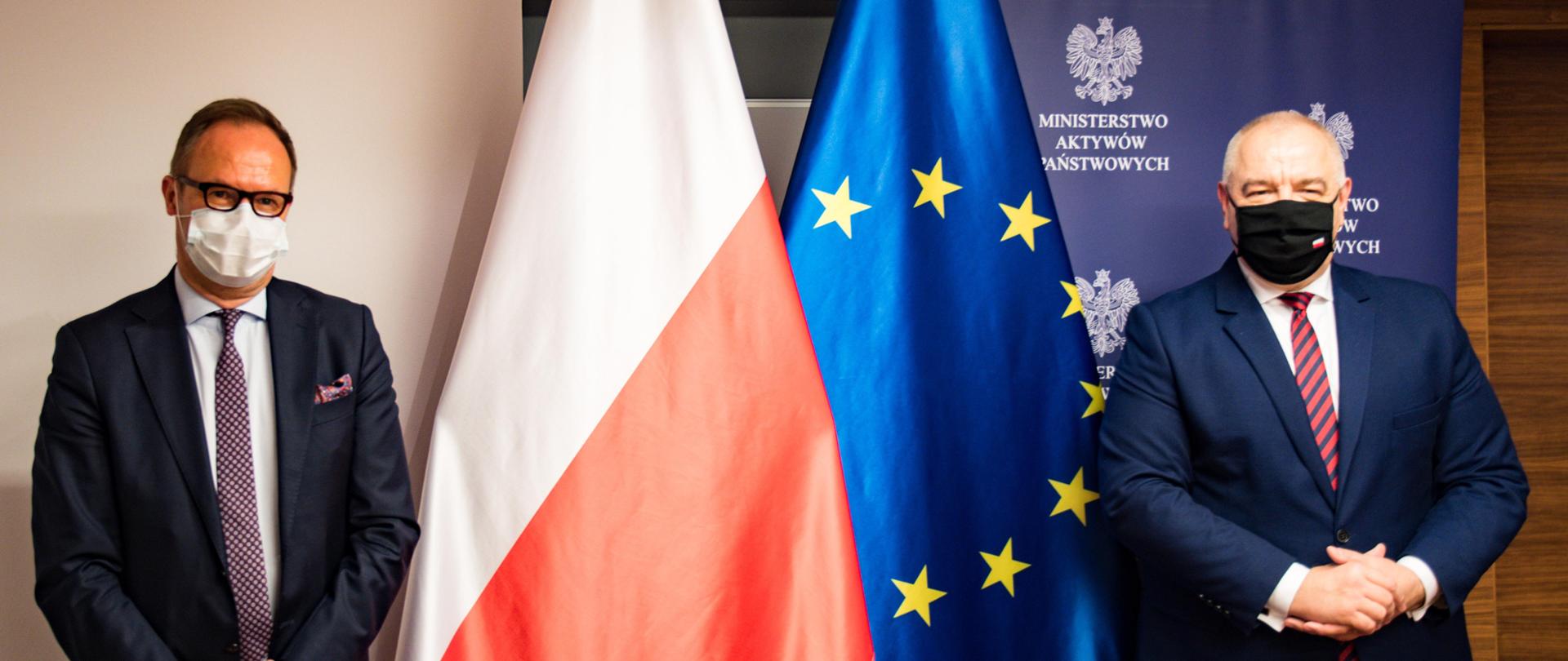 Wicepremier Jacek Sasin i ambasador Finlandii Juha Ottman stoją na tle flag Polski i Unii Europejskiej