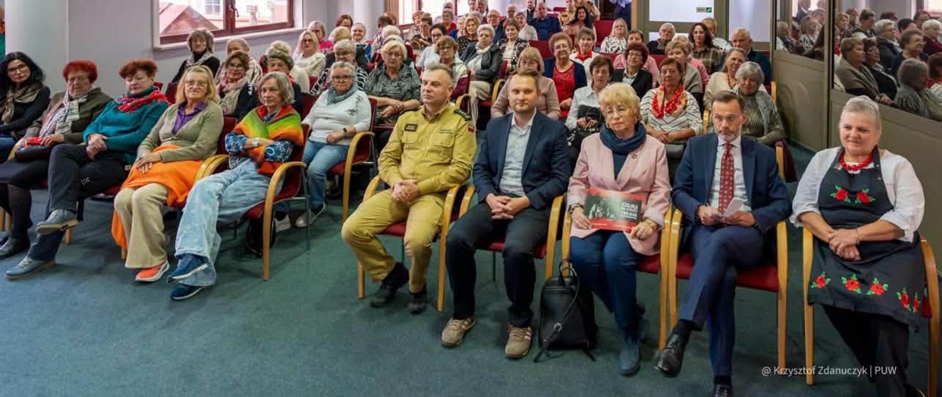 16 października w Podlaskim Urzędzie Wojewódzkim odbyła się konferencja „Bezpieczny senior w sezonie grzewczym” - sala pełna seniorów na czele z organizatorami i prelegentami wydarzenia - wszyscy siedzą na krzesłach w sali
